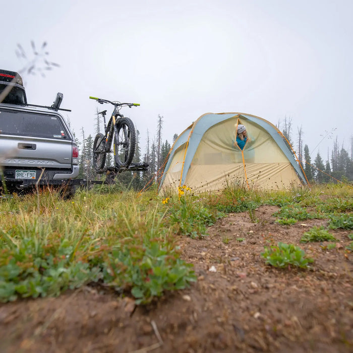 A Big Agnes Accessory Mesh Insert for the Sage Canyon Shelter Plus and a bike-mounted vehicle are set up on muddy grass in a foggy area with sparse trees—an ideal spot to organize your gear.