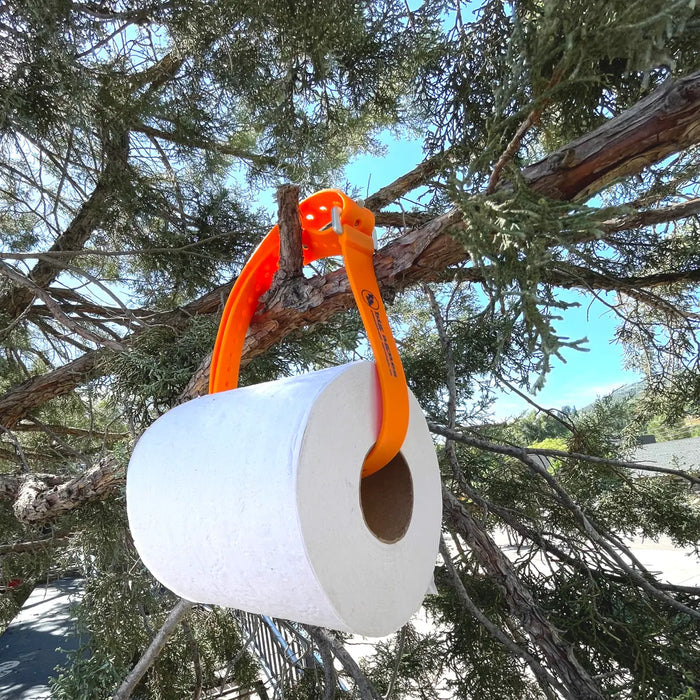 White camping toilet with orange handle hanging from a tree