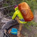 Hiker with an orange backpack and a dog in a forest