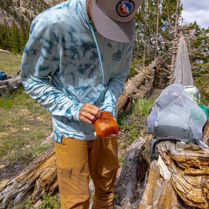Person in outdoor setting with hiking gear and hats on a log