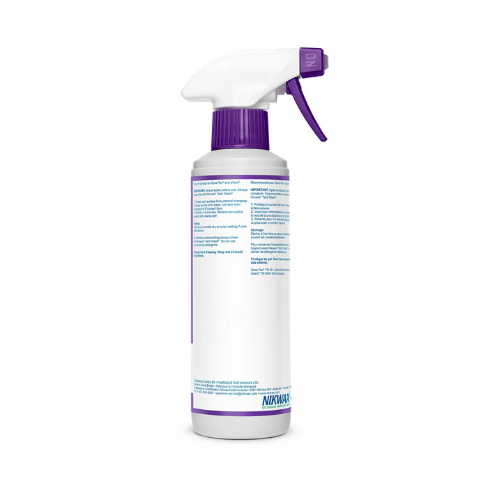 A white spray-on bottle with a purple nozzle and trigger is shown against a plain background. The label displays Big Agnes Nikwax TX Direct Spray-On Waterproofing 10 oz., for restoring water-repellency to synthetic outerwear.