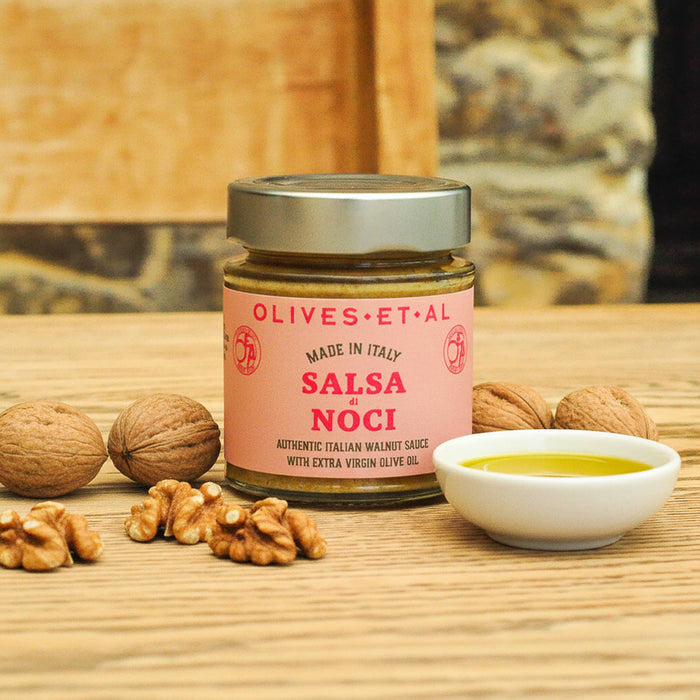 olives et al - jar of salsa di noci on wooden table with nuts and olive oil next to it - winter's moon