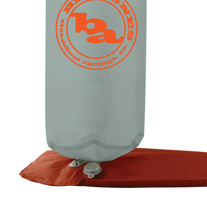 A gray Pumphouse Ultra HyperBead™ pump sack by Big Agnes with orange branding and Steamboat Springs, CO text is connected to a red inflatable sleeping pad via a valve for easy inflation.