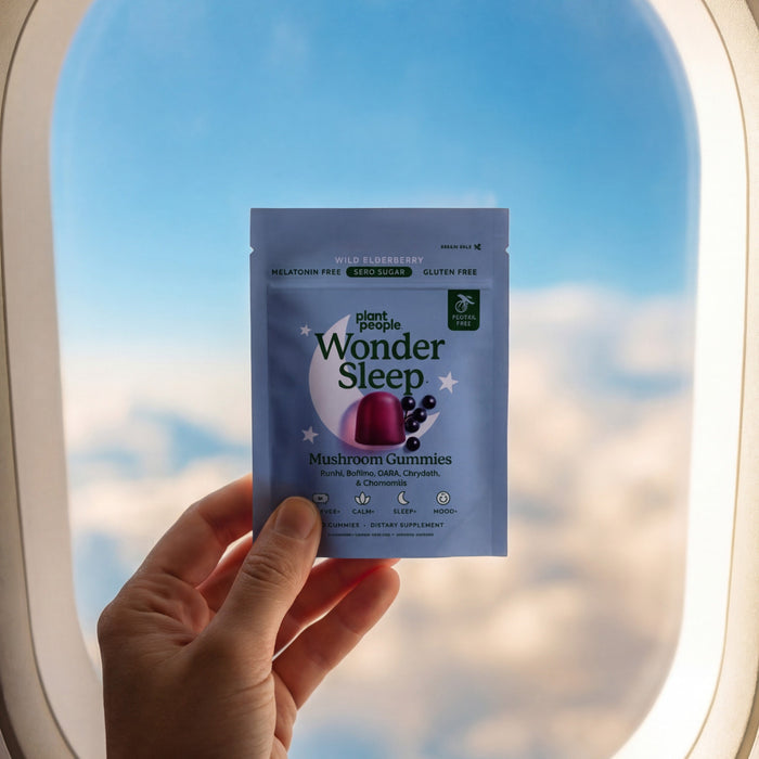 Hand holding a 'Wonder Sleep' product package in front of an airplane window with a view of clouds and sky.
