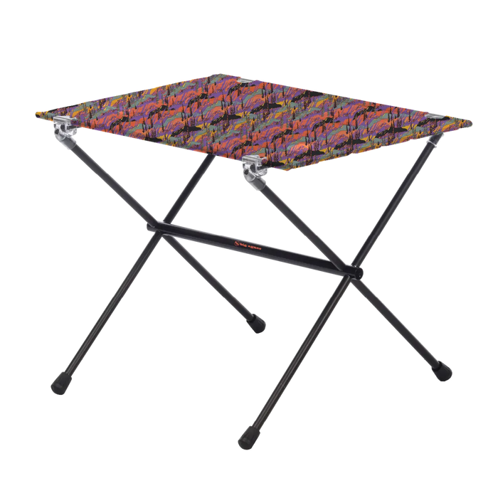 The Big Agnes Woodchuck Camp Table - Alpenglow is a lightweight, foldable outdoor table featuring black metal legs and a rectangular top with a colorful abstract design, shown on a plain white background.
