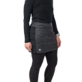 A person wearing a black long-sleeve shirt, black leggings, and the Big Agnes W's Columbine Skirt with diamond quilting stands against a plain white background.