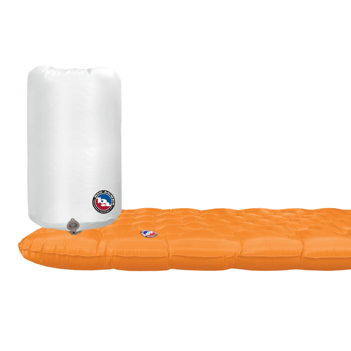 The Big Agnes Zoom UL Insulated, an orange ultralight sleeping pad, is partially inflated beside a white air pump sack, both showing the Big Agnes logo on a plain white background.